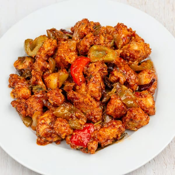 Guru Palace's chili chicken, featuring crispy chicken pieces, bell peppers, and onions in a spicy sauce.