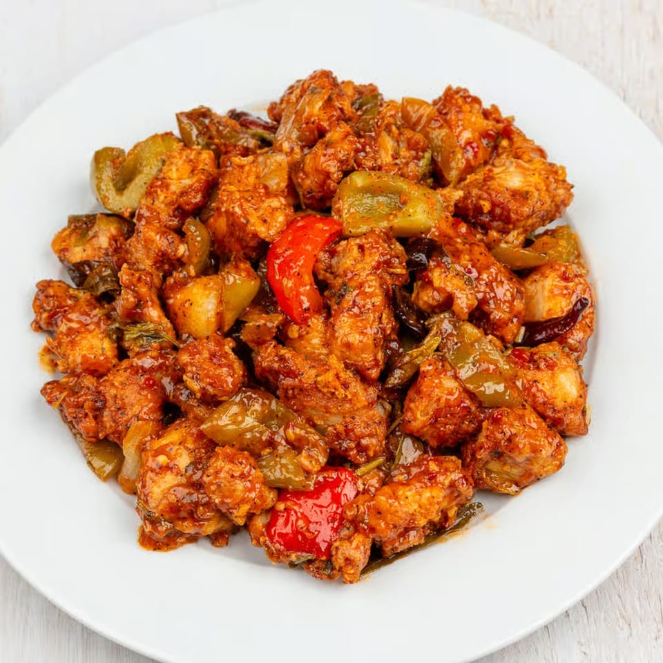 Guru Palace's chili chicken, featuring crispy chicken pieces, bell peppers, and onions in a spicy sauce.